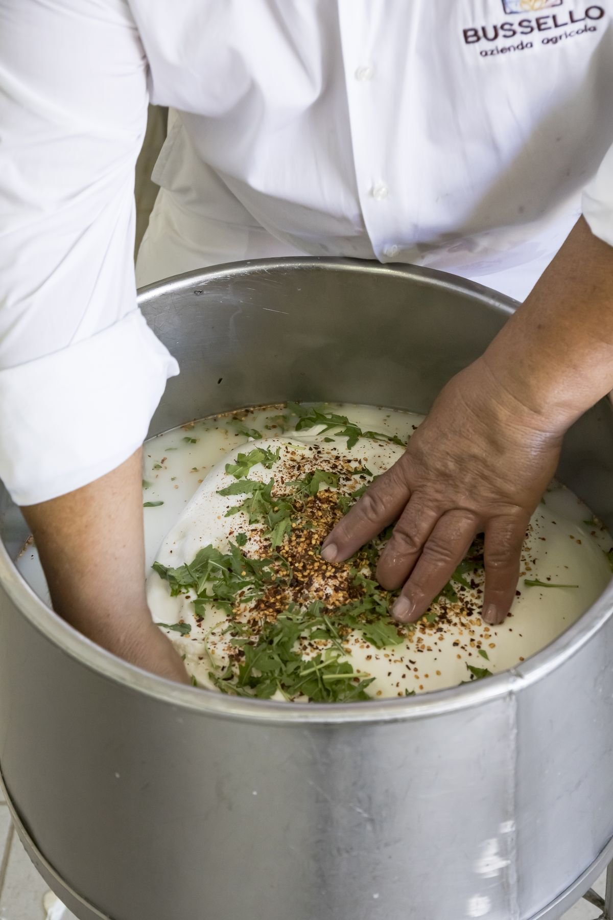 Le mani del casaro lavorano la pasta filata nella caldaia