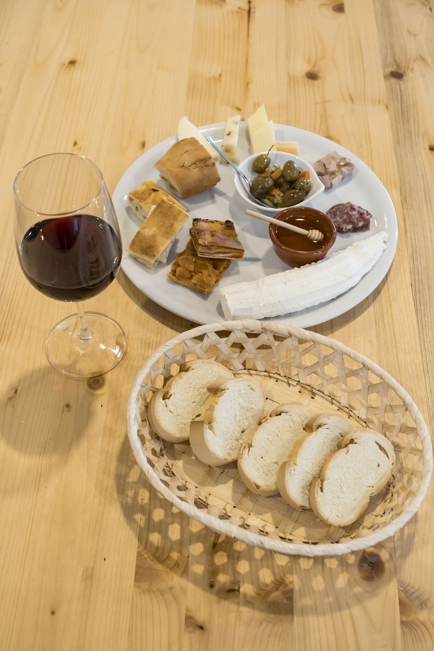 Tagliere di formaggi, scacce e olive con un calice di vino